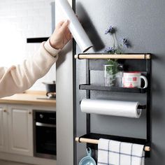 a woman is holding up a roll of toilet paper on a rack in the kitchen