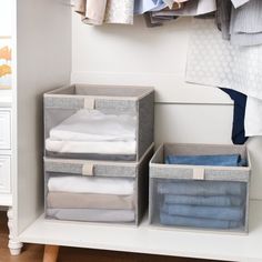 the closet is organized with three bins and folded clothes hanging on hooks, along with other storage containers