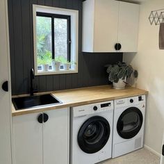 a washer and dryer sitting in a kitchen next to a window with potted plants