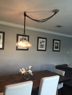 a dining room table with white chairs and pictures hanging on the wall above it,