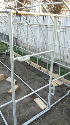 a white metal frame in the middle of a yard with some wood planks attached to it