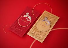 two red and gold greeting cards sitting on top of a red surface with golden string