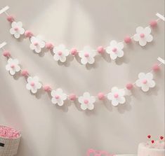 pink and white paper flowers are hanging from the wall next to a baby's crib