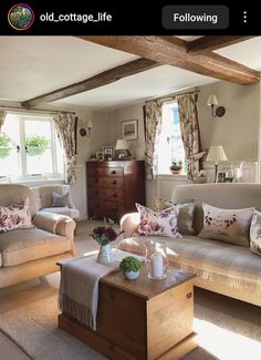 a living room with two couches, a coffee table and some flowers in vases