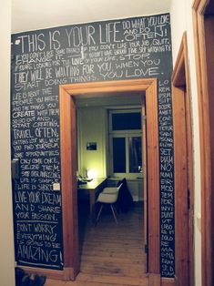 a blackboard wall with writing on it and a door leading to the bathroom area