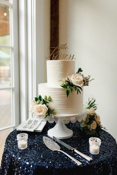 a white wedding cake sitting on top of a table next to utensils and candles