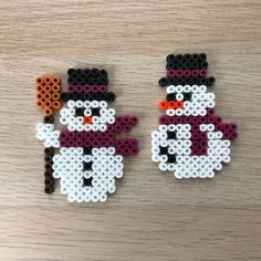 two snowmen made out of legos sitting on top of a wooden table