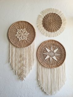 two wall hangings made out of wicker with fringe and star designs on them