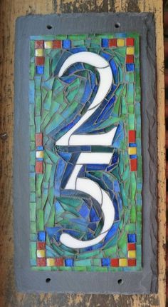 a decorative tile with the number twenty five in blue, green and red colors on it