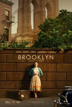 a woman standing in front of a brick wall with the words brooklyn written on it