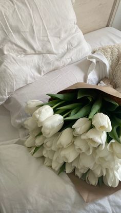 a bouquet of white tulips on a bed