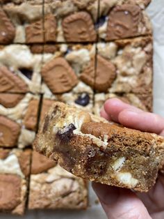 a hand holding up a cookie bar with chocolate chips and marshmallows on it