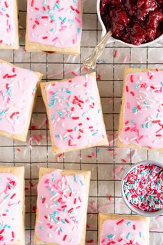 strawberry shortbreads with pink frosting and sprinkles on a cooling rack