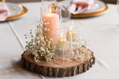 a wooden table topped with candles and flowers on top of a white table cloth covered table