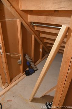 an unfinished room with wood framing and tools on the floor, including hammers and plywood