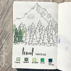 an open notebook with trees and mountains drawn on it