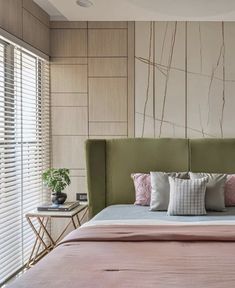 a bed with pink sheets and pillows next to a window in a room that has blinds on the windowsill