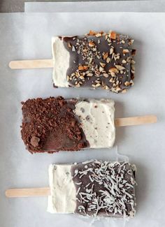 three different types of ice cream on sticks with chocolate toppings and nuts in them