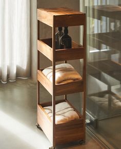 a wooden shelf with two bottles on it and some pillows in front of the window