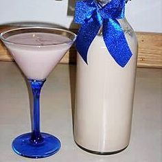 a drink in a glass next to a bottle with a blue bow on the top