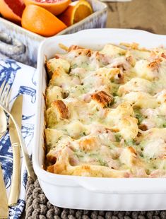 a casserole dish with meat and cheese in it on a table next to oranges