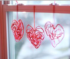 three red hearts hanging from a window sill