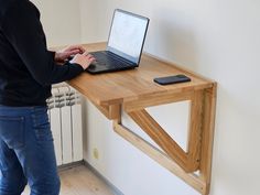 a person using a laptop computer on a wooden desk in front of a radiator