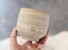 a hand holding a small wooden bowl with the word d on it's side