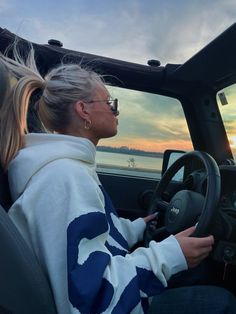 a woman sitting in the driver's seat of a truck with her hand on the steering wheel