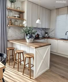 a kitchen with white cabinets and wooden counter tops, an island in front of the sink