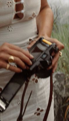 a woman in white dress holding a cell phone and carrying a brown leather bag with gold accents