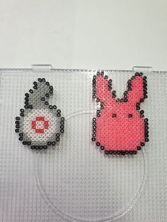 two pieces of bead art on a white surface with black and pink beads in the shape of animals