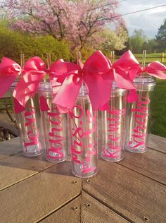 six personalized tumblers with pink bows are sitting on a picnic table