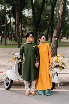 a man and woman standing next to each other near a scooter