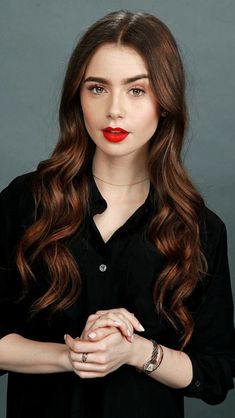 a woman with long brown hair wearing a black shirt and red lipstick on her lips