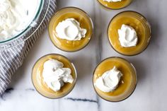 four desserts with whipped cream on top in small glass dishes next to a bowl