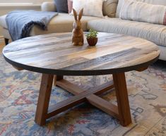 a wooden table with a potted plant on it in front of a couch and rug