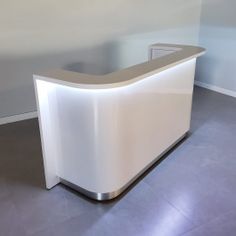 a white reception table with a silver base and light colored counter top in an empty room