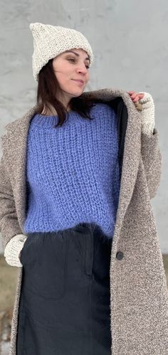 a woman wearing a blue sweater and black skirt