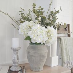 a vase filled with white flowers sitting on top of a table next to a candle