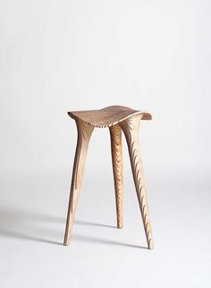 a small wooden stool sitting on top of a white floor next to a table with two legs