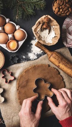 a person holding a cookie in front of some cookies and other baking supplies on a table