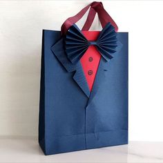 an origami bag with a bow tie and shirt on the front, sitting on a table