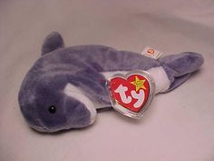 a stuffed dolphin with a heart shaped tag on it's neck and nose is laying down