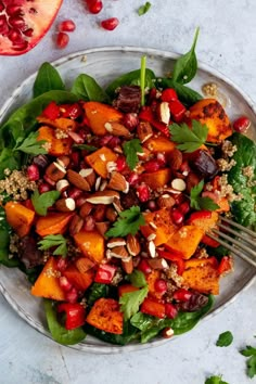 a salad with nuts, spinach and pomegranates on a plate