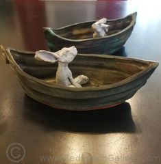 two small wooden boats with figurines in them