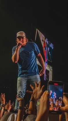 a man standing on top of a stage while holding a cell phone in his hand