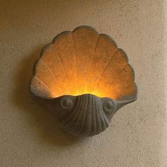 a scallop shell shaped light fixture mounted on the side of a stucco wall