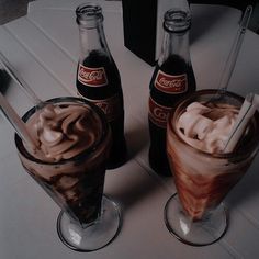 two beverages are sitting on a table next to each other, one is chocolate and the other has marshmallows