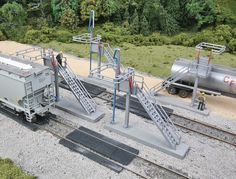 a model train set up on the tracks with stairs leading to an oil tank and other equipment